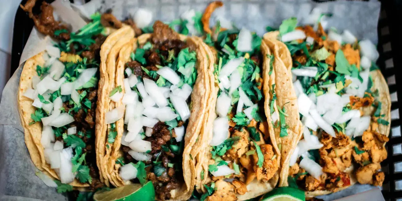 Fünf köstliche Tacos mit Rindfleisch und Hähnchen, garniert mit Zwiebeln und Koriander. Perfekt für einen Taco-Abend!